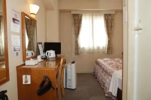 um quarto de hotel com uma cama, uma escrivaninha e uma janela em アイリスイン知立 em Chiryu
