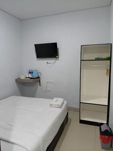 a white room with a bed and a tv at Raja Soeta Express Syariah in Hajimana