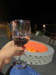 a person holding a glass of wine in front of a fire pit at Refúgio Premium nas Montanhas de Alfredo Chaves Refúgio nas Montanhas de Alfredo Chaves com Piscina Jacuzzi Aquecida externa Suite Master com Hidro e Área Gourmet in Alfredo Chaves +51 photos