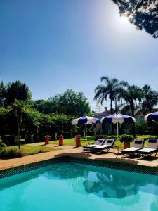 a swimming pool with lounge chairs and umbrellas at Casa para familias y grupos in Manises