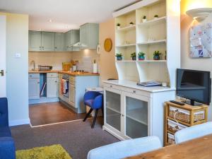 cocina con armarios azules y mesa con TV en County House Apartment - 27911, en York
