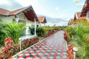 a walkway in front of a house with red flowers at Coorg Crown Palace Resort kushalnagar in Jāmb +3 photos