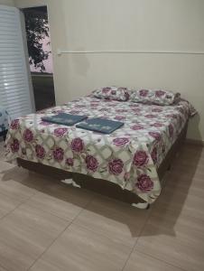 a bed with a floral comforter in a room at pousada recanto do coelho in Roseira +39 photos
