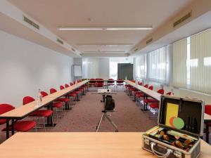 an empty classroom with tables and chairs and a tv at ibis Stuttgart Airport Messe in Leinfelden-Echterdingen