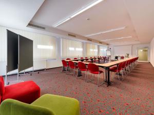 a conference room with a long table and red chairs at ibis Stuttgart Airport Messe in Leinfelden-Echterdingen