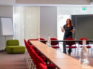 a woman standing in a room with tables and chairs at ibis Stuttgart Airport Messe in Leinfelden-Echterdingen