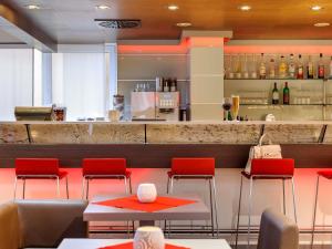 a restaurant with red chairs and a counter at ibis Stuttgart Airport Messe in Leinfelden-Echterdingen