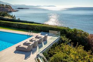 a house with a swimming pool next to the ocean at Paradise Beachfront Villa Athenian Riviera in Aghia Marina