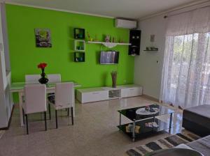 a living room with a green wall and a table and chairs at Apartment Duje Dazlina in Dazlina