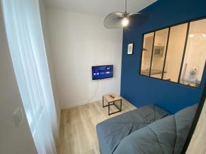 a living room with a blue wall and a tv at Logement Neuf Cosy avec Espaces Communs Premium 12 in Belfort