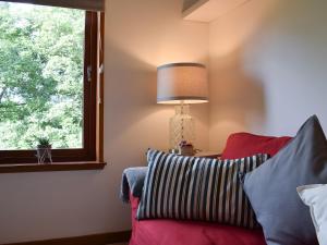 a lamp sitting next to a red couch with a window at Tree Tops in Crieff