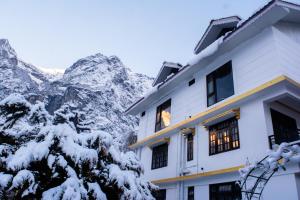 a building with snow covered mountains in the background at Mystique Valley by Trekocity in Lachung