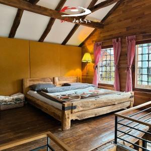 a bedroom with a large bed in a room with wooden walls at Whispering Pines Villa in Peje