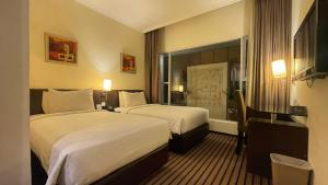 a hotel room with two beds and a desk at Harmoni One Convention Hotel and Service Apartments in Batam Center +36 photos