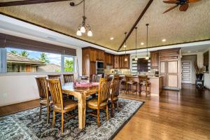 Una cocina y un comedor con mesa y sillas de madera. en Tropical Villa wPrivate Pool Golf Course Views, en Waikoloa