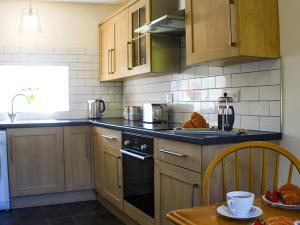 una cucina con armadi in legno e forno a piano cottura nero di Apple Tree Cottage a Bassenthwaite Altre 11 foto