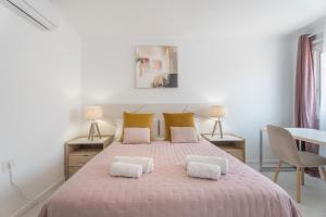 a white bedroom with a pink bed with two pillows at Apartamento Afirama 1 in Araya +21 photos