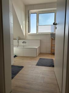 une salle de bain avec une baignoire, un lavabo et une fenêtre dans l'établissement Feriennest am Wangermeer, à Wangerland