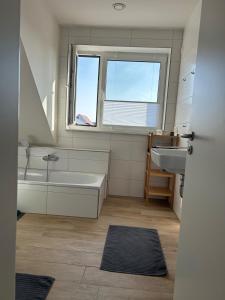 une salle de bain avec une baignoire, un lavabo et une fenêtre dans l'établissement Feriennest am Wangermeer, à Wangerland 41 autres photos