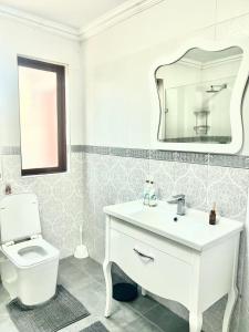 a white bathroom with a sink and a toilet at Big 5 Cottage in Pretoria