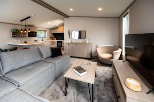 セント・アンドルーズにあるHot tub Lodge, Victory 101のリビングルーム(グレーのソファ付)、キッチンが備わります。