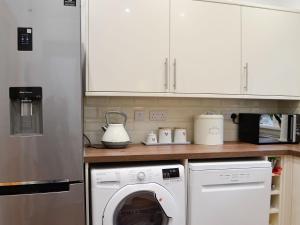 eine Küche mit einem Kühlschrank und einer Waschmaschine in der Unterkunft Rhona's Cottage in Abergavenny + 12 Fotos