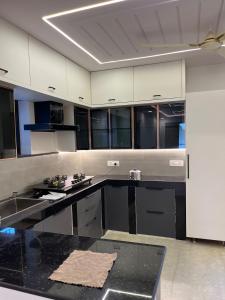 a large kitchen with black counters and white cabinets at Peaceful Private Residence in Hyderabad +3 photos