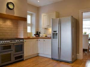 a kitchen with a refrigerator and a clock on the wall at Rowan House in Threlkeld +20 photos