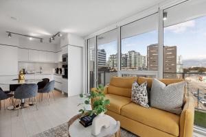 バンクーバーにあるModern 3BR Condo with Rooftop, Gym and Parking near Skytrainのリビングルーム(黄色のソファ付)、キッチンが備わります。
