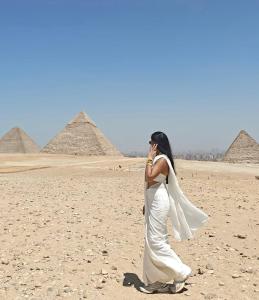 Kafret el-GabalMk Pyramids View的一位身穿白色连衣裙的女子走在金字塔前