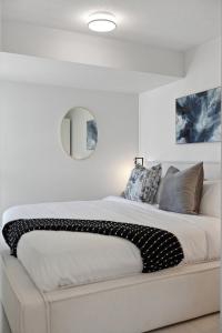 バンクーバーにあるModern 3BR Condo with Rooftop, Gym and Parking near Skytrainの白いベッドルーム(鏡付きの大型ベッド1台付)