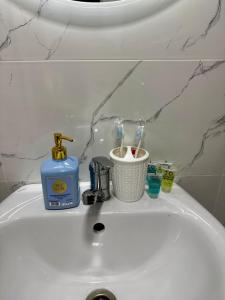 a bathroom sink with a soap dispenser and tooth brushes at Квартира - Терракота in Ustʼ-Kamenogorsk