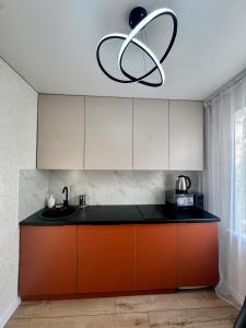 a kitchen with a sink and a chandelier at Квартира - Терракота in Ustʼ-Kamenogorsk +4 photos