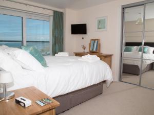 a bedroom with a large white bed and a window at Apartment 11 - Latitude 51 in Westward Ho