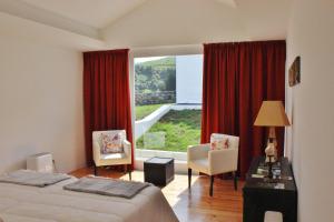 a bedroom with two beds and a large window at Aldeia do Priolo in Nordeste