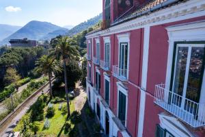 カステッランマーレ・ディ・スタービアにあるJunior Suite Relais al Castelloのヤシの木と山々を背景にしたピンク色の建物
