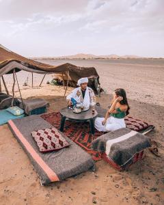 Un hombre y una mujer sentados en una mesa en la playa en Sahara Erg Chebbi Camp, en Merzouga