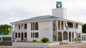 ItaquiHOTEL KAMPÔ Suítes的一座白色的大建筑,顶部设有钟楼