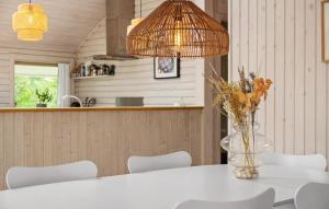 a table with white chairs and a vase with flowers at Lovely Home In Dronningmølle With Wifi in Dronningmølle