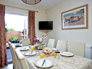 a dining room with a table with chairs and a television at Cormorant View in Weymouth