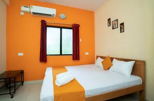 a bedroom with a bed with orange walls and a window at Kitu & Kim Apartments in Calangute +1 photo