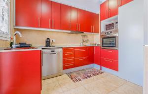 a red kitchen with white appliances and red cabinets at 3 Bedroom Stunning Home In Miami Platja in Miami Platja