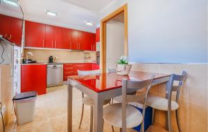 a kitchen with red cabinets and a table and chairs at 3 Bedroom Stunning Home In Miami Platja in Miami Platja