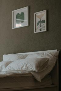 a bed with white sheets and two pictures on the wall at Stylish apartment mit Bachblick in Vallendar