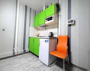 una cocina con armarios verdes y una silla naranja en Безпечні апартаменти на цокольному поверсі біля метро, en Járkov 2 fotos más