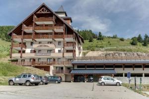ein großes Gebäude mit auf einem Parkplatz abgestellten Autos in der Unterkunft Appartement moderne avec vue incroyable in Les Deux Alpes