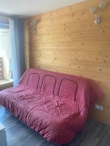 ein Schlafzimmer mit einem rosa Bett und einer Holzwand in der Unterkunft Appartement moderne avec vue incroyable in Les Deux Alpes