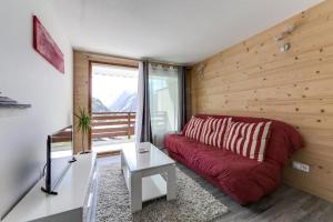 ein Wohnzimmer mit einem roten Sofa und einem Fenster in der Unterkunft Appartement moderne avec vue incroyable in Les Deux Alpes