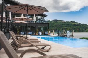 a pool with chairs and umbrellas next to a building at noi Resort SPA - woda i las in Tęgoborze
