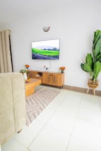 un salon avec un canapé et une télévision au mur dans l'établissement Serene Spaces Garden Estate, à Gatunga